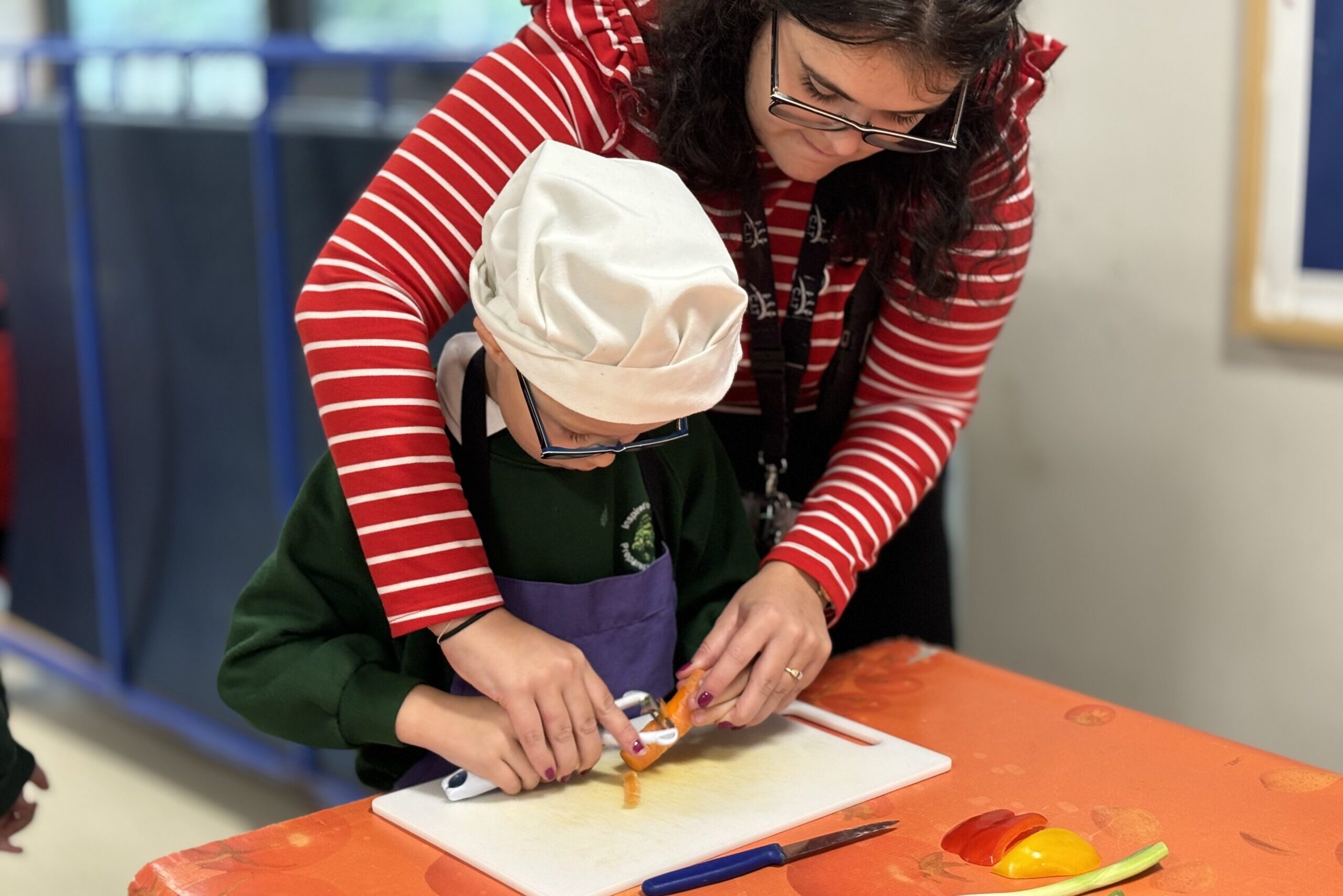 Staff member helping a pupil in cookery