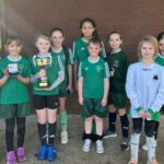 The teams stand together with their trophies