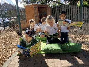 children sitting on some decking reading outside